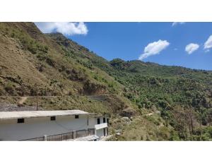 a view of a mountain with a building and a road at Sandeep Home stay, Chakrata in Chakrāta