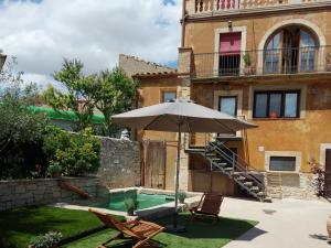 a patio with an umbrella and chairs and a pool at La Festa dels Sentits in Sant Martí de Maldá