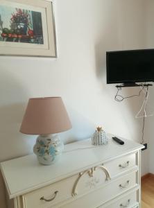 a lamp sitting on top of a dresser with a television at Bilocale NICOL 4 posti Padova ovest in Padova