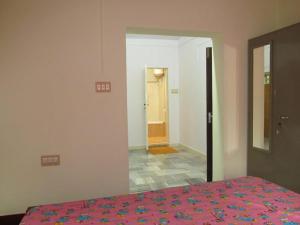 a bedroom with a bed and a hallway with a door at Gladsvilla in Mangalore