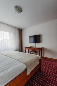 a bedroom with a bed and a desk and a television at Boutique Damiani in Sibiu