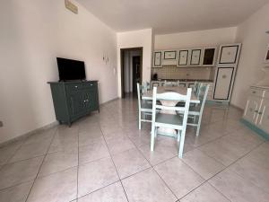 een woonkamer met een tafel, stoelen en een televisie bij Casa Mario e Rosa in Orosei