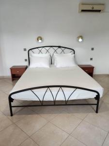 uma cama com lençóis brancos e almofadas num quarto em Tilos Fantasy em Livadia