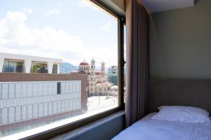 a bedroom with a window with a view of a city at Bocca Hotel Korce in Korçë