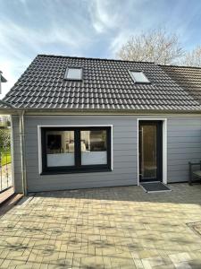 a house with a shingled roof and a patio at Idyllisches Ferienhäuschen Rendsburg in Rendsburg