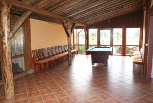 a large room with a pool table and benches at Wilimy, Domek Przy Stawie in Biskupiec