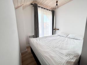 加茨比亞格拉的住宿－Domki Yellow Hill Jastrzębia Góra，卧室配有白色的床和窗户。