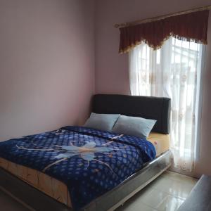 - une chambre avec un lit avec une couette bleue et 2 fenêtres dans l'établissement Homestay wahyu abadi 2 syariah, à Diyeng