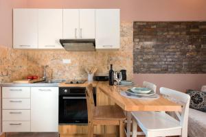 una cocina con armarios blancos y una mesa con sillas. en Nikas Guest House en Kanálion