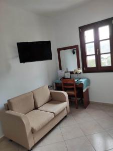 a living room with a couch and a television on the wall at Tilos Fantasy in Livadia
