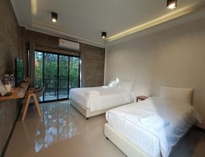 a hotel room with two beds and a balcony at บ้านสวนคุณปาน เขาใหญ่ Ban Suan Kun Parn Khao Yai in Mu Si