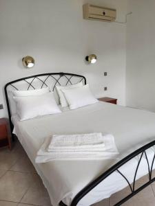 a white bed with white sheets and pillows at Tilos Fantasy in Livadia
