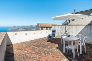 un patio con mesa, sillas y sombrilla en IL MONTE - Suite Con Terrazza Panoramica, en Erice