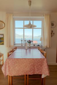 a dining room with a table and a large window at Lovely 4-BR house / Sea view / Nature in Oyndarfjørður