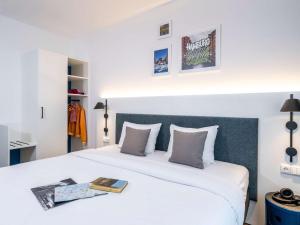 a bedroom with a large white bed with a book on it at ibis Styles Hamburg Alster City in Hamburg