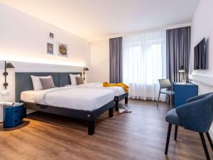 a hotel room with two beds and a chair at ibis Styles Hamburg Alster City in Hamburg