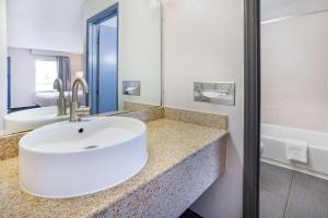 uma casa de banho com um lavatório branco e um espelho. em Days Inn by Wyndham Raleigh Glenwood-Crabtree em Raleigh