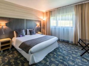 ein Hotelzimmer mit einem großen Bett und einem Fenster in der Unterkunft Mercure Annecy Sud in Annecy