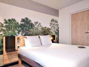 Un dormitorio con una gran cama blanca y una pared con árboles en Novotel Suites Montpellier Antigone, en Montpellier