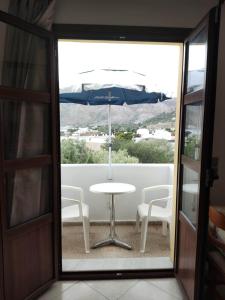 d'une table, de chaises et d'un parasol sur le balcon. dans l'établissement Tilos Fantasy, à Livadia