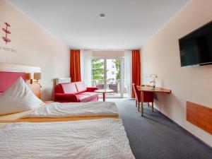 a hotel room with a bed and a desk and a television at Hotel Häfner in Bad Schonborn