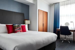 um quarto de hotel com uma cama grande e uma secretária em The Cumberland, London em Londres