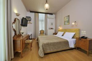 1 dormitorio con cama, escritorio y espejo en Dryades & Orion Hotel, en Atenas