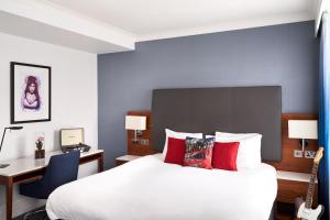 a bedroom with a bed and a desk with a guitar at The Cumberland, London in London