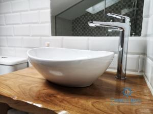 a white bowl sink on a wooden table in a bathroom at Cabanela Maitia Apto Telmo Duplex in Ribadeo