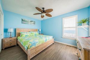 1 dormitorio azul con 1 cama y ventilador de techo en 19th Hole, en Whalebone