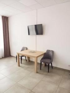a wooden table with two chairs and a television on a wall at PREMIUM - 24 Betten - 9 Appartements zentral in Oer-Erkenschwick - homes of ruhr in Oer-Erkenschwick