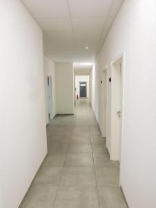 un couloir vide avec des murs blancs et du carrelage dans l'établissement PREMIUM - 24 Betten - 9 Appartements zentral in Oer-Erkenschwick - homes of ruhr, à Oer-Erkenschwick