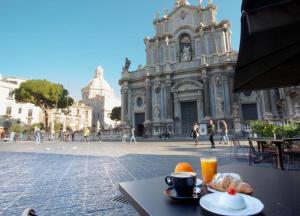 Duomo Luxury Suite Catania في كاتانيا: طاولة مع كوب من القهوة وصحن من الطعام