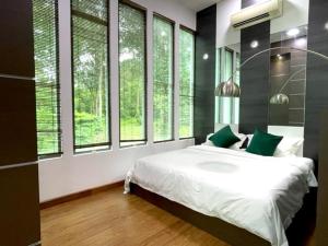 a bedroom with a bed with green pillows and windows at Teluk Cempedak Seventh Haven in Kuantan