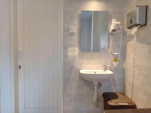 bagno bianco con lavandino e specchio di Simple Kuta Bedroom a Denpasar