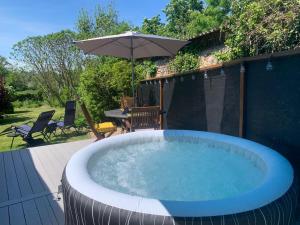 a hot tub in a backyard with an umbrella at The Yurt at Les Forges in Saint-Sornin-la-Marche