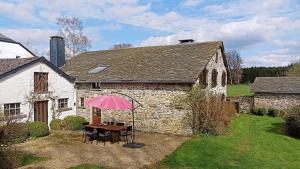 a house with a table with a pink umbrella at Gite : Le vi colombage de Petites-Tailles in Vielsalm