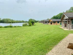 a large grassy field next to a row of cottages at Kingfisher Lodge, Lake Pochard in South Cerney