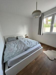 Bett in einem weißen Schlafzimmer mit Fenster in der Unterkunft Moderne Wohnung mit 4 Betten in Bochum