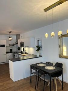 una cocina con mesa negra y sillas y una cocina con armarios blancos. en Moderne Wohnung mit 4 Betten en Bochum
