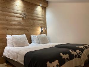 a bedroom with a large bed with a wooden wall at Le Lodge Chasse Montagne in Les Gets +3 photos