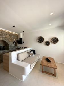 Quattro Venti Suites Mykonos في تورلوس: غرفة معيشة مع أريكة بيضاء وطاولة