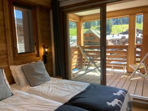 a bedroom with a bed and a balcony with a view at Le Lodge Chasse Montagne in Les Gets