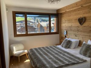 a bedroom with a bed and a window and a chair at Le Lodge Chasse Montagne in Les Gets