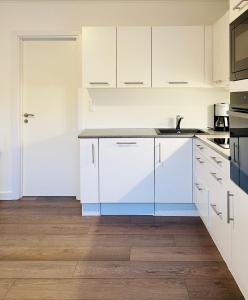 una cocina con armarios blancos y fregadero en Scandinavian Apartment Hotel - Lunden 1 - Central 3 bedroom apartment on two floors, en Horsens