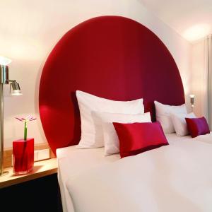 a bedroom with two beds with red and white pillows at ARCOTEL Rubin Hamburg in Hamburg
