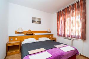 Un dormitorio con una cama con sábanas moradas y una ventana en Apartments Klis, en Mlini