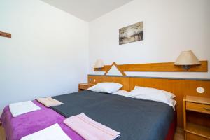 1 dormitorio con 1 cama grande con manta morada en Apartments Klis, en Mlini