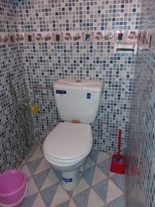 La salle de bains est pourvue de toilettes blanches et d'un mur carrelé. dans l'établissement Oisis Mazagan 2, à El Jadida