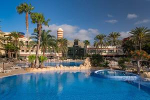 duży basen z palmami i ośrodek w obiekcie Elba Carlota Beach & Golf Resort w mieście Caleta De Fuste